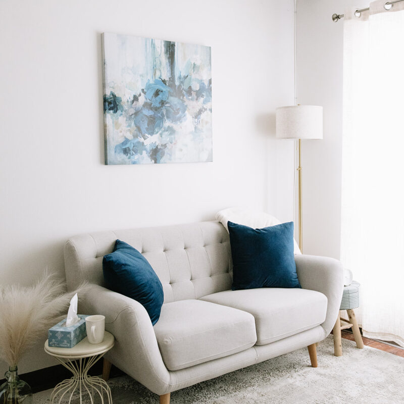 Inviting therapy space at The Mindful Place in Cambridge Ontario with a grey loveseat and calming design.