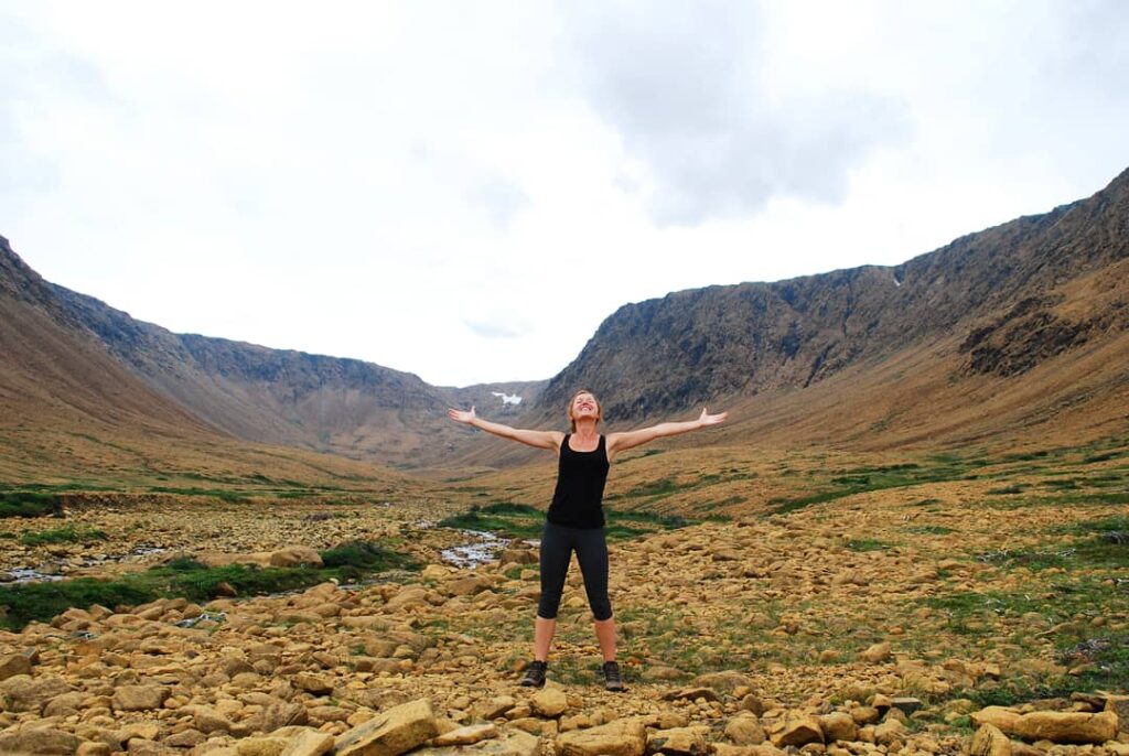 Chantale standing with open arms in a mountain landscape, symbolizing self-acceptance, inner peace, and freedom through self-compassion practices at The Mindful Place in Ontario.