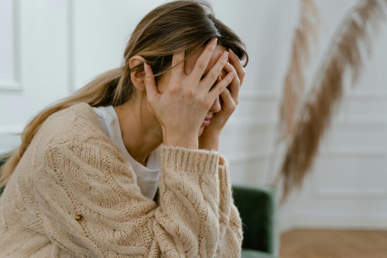 Person sitting with their head in their hands, reflecting the emotional overwhelm and distress that can follow traumatic experiences, at The Mindful Place in Ontario.