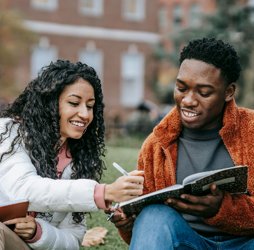 Two people sitting together outdoors, sharing a journal and smiling, representing connection, support, and healthy ways of managing stress, at The Mindful Place in Ontario.