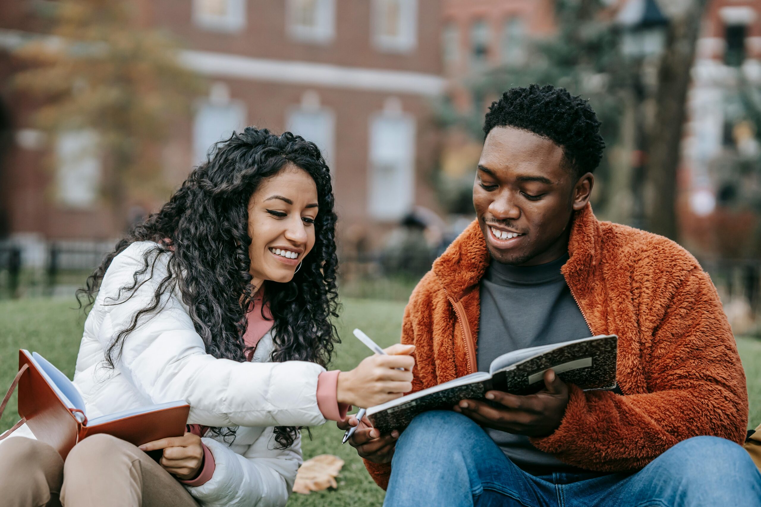 Two people sitting together outdoors, smiling and reviewing a notebook, symbolizing collaboration, clarity, and the supportive strategies explored in work–life balance presentations at The Mindful Place in Ontario.